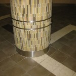 close up view of stainless steel ornamental piece and baseboard on round column with colorful tile