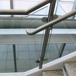 end of fabricated metal railing and frame on glass