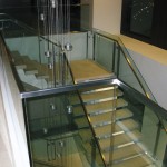 top of stairway view of metal handrail on glass panels