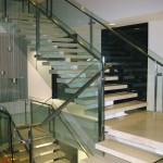 detailed side view of metal handrail on glass panel stairway